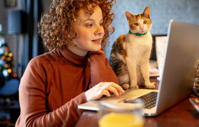 Young software developer with cat using laptop