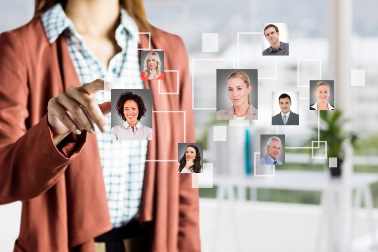 A female tech recruiter is interacting with a digital interface displaying a network of professional headshots of software developers and IT workers.