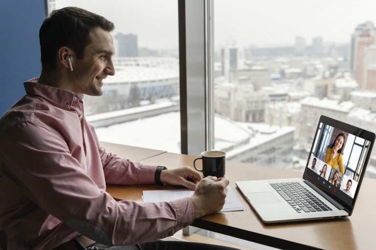 Remote software developer smiles at his laptop screen during a video conference with co-workers