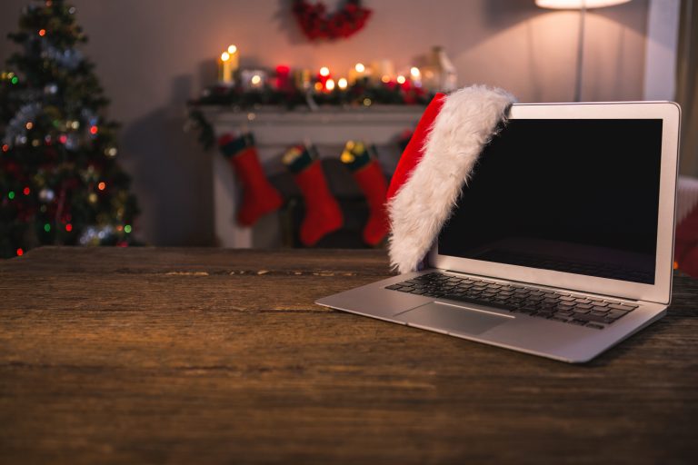 Laptop with a Santa hat on a desk, symbolizing a tech worker’s out-of-office status during the Christmas holidays