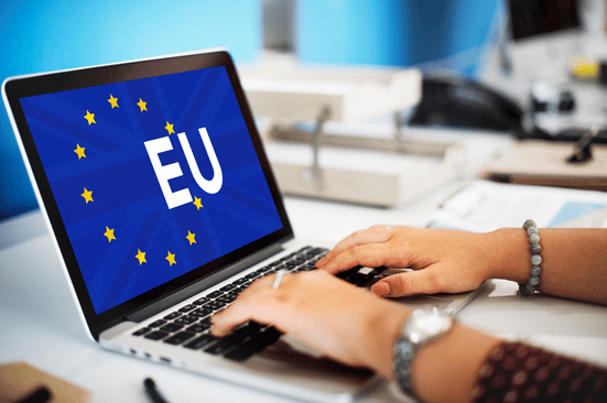 The Clock Is Ticking: How To Prepare for the EU Pay Transparency Directive Close-up of a person typing on a laptop displaying the European Union flag and the letters “EU” on screen. The image represents EU policy and legislation, and illustrates the EU Pay Transparency Directive