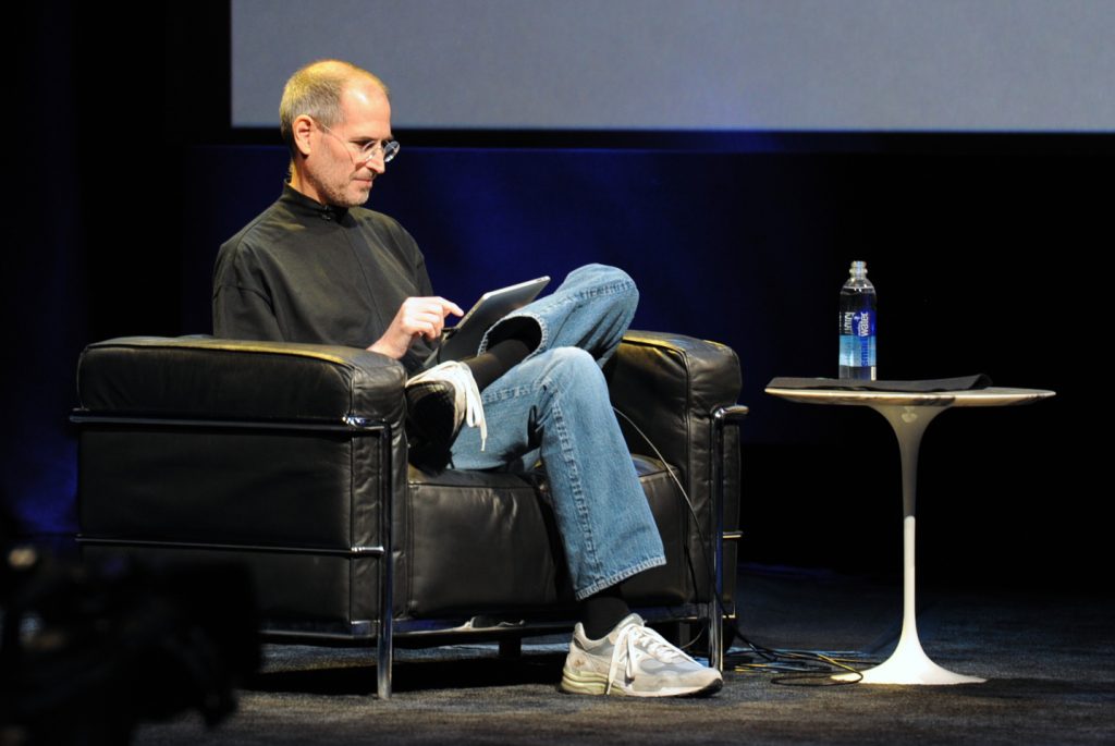 Steve Jobs announces the iPad in San Francisco on 27 January 2010. Seated cross-legged in a black leather armchair, he uses an iPad while wearing his signature outfit: a black mock turtleneck, blue jeans, and white sneakers. Picture: Matt Buchanan/Wikimedia Commons