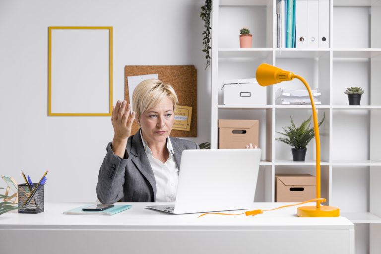 A frustrated office worker gestures behind a laptop